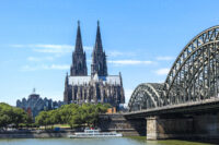 Deutschland, Köln, Blick auf den Kölner Dom mit gutbesuchter Hohenzollernbrücke. Im Vordergrund der Rhein.