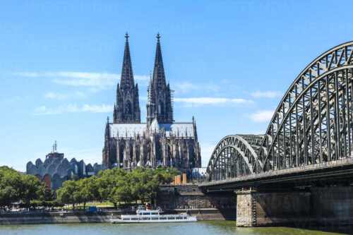 Deutschland, Köln, Blick auf den Kölner Dom mit gutbesuchter Hohenzollernbrücke. Im Vordergrund der Rhein.